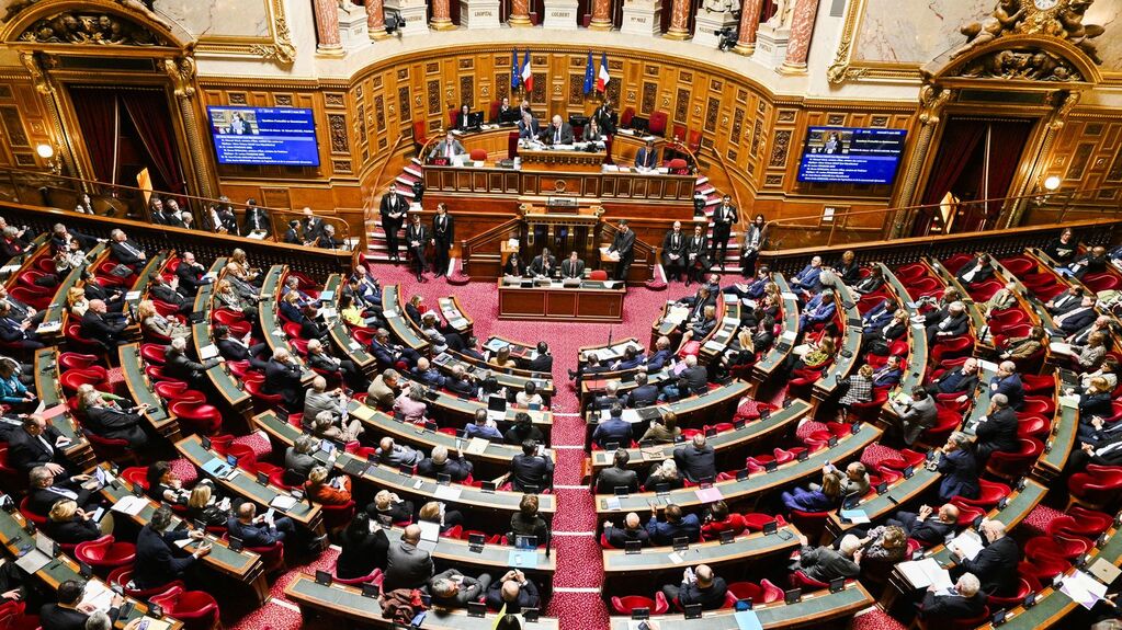 Photo prise en hauteur d’un hémicycle parlementaire français, je ne sais pas lequel, où les deux tiers des parlementaires sont absents, la photo est prise à peu près en face du bureau où siège lae président⋅e de l’assemblée